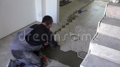 建筑工人在地板上放六边形瓷砖。 安装石材瓷砖